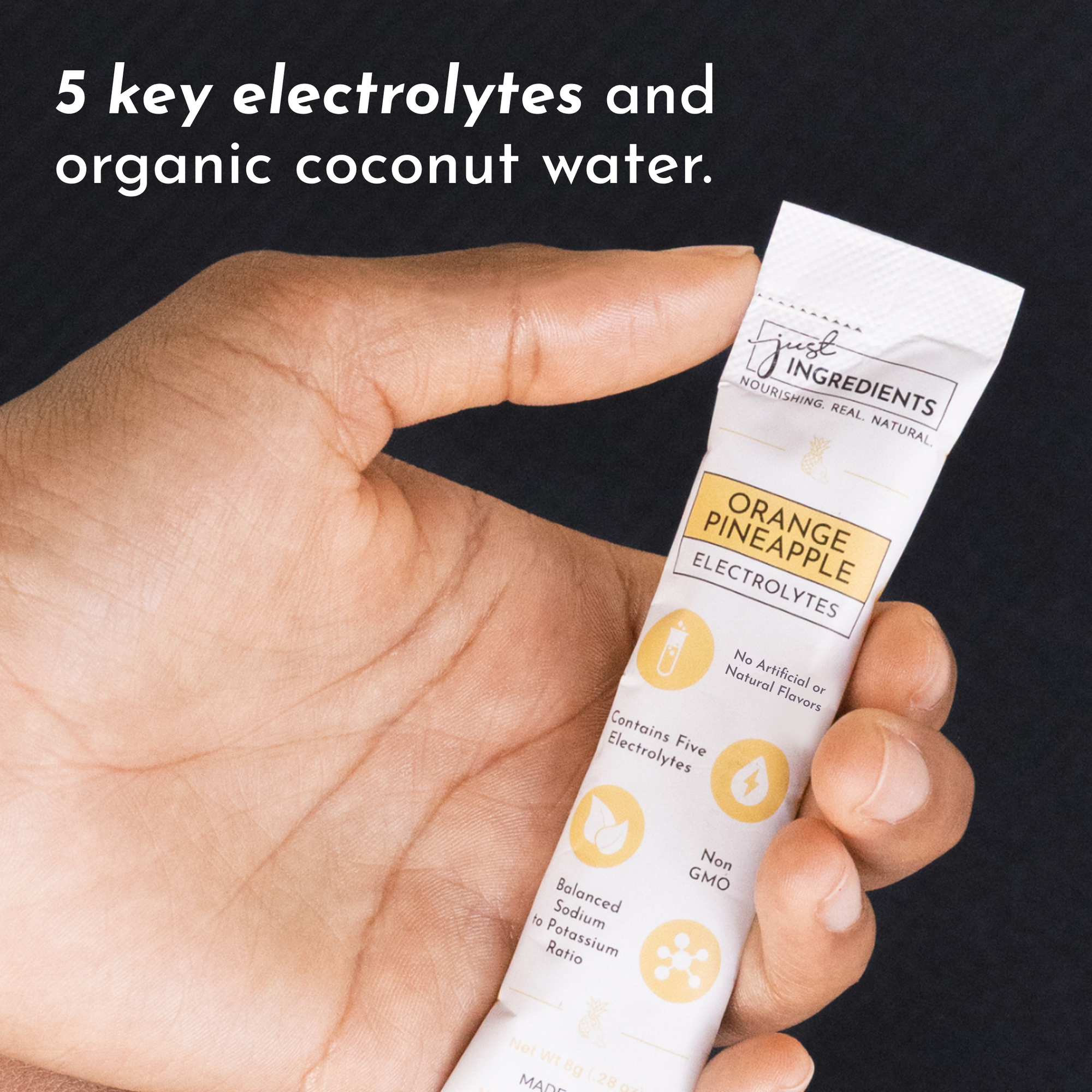 Hand holding a stick packet labeled "Orange Pineapple Electrolytes" with nutritional information visible.