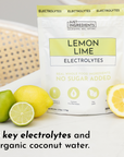 Pouch of Lemon Lime Electrolytes with whole lemons and limes on a surface, highlighting key ingredients.