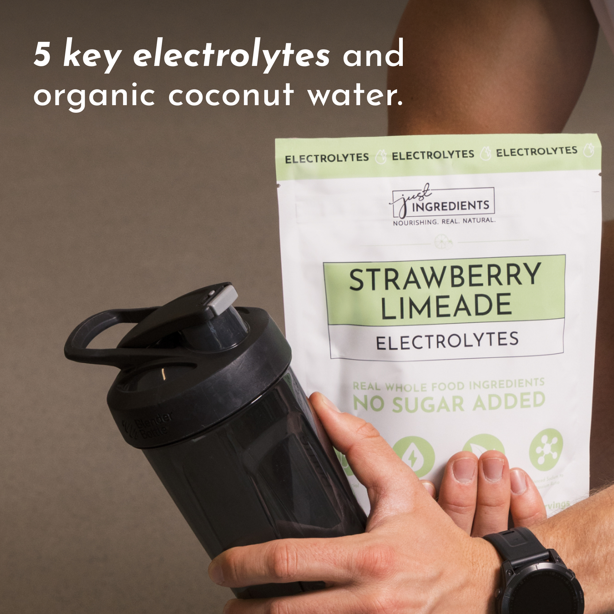 A person holds a shaker bottle and a package of Strawberry Limeade Electrolytes featuring key ingredients.