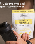 Pouch of Tropical Paradise Electrolytes with a shaker bottle, highlighting key ingredients and no sugar added.
