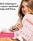 A woman holds a packet of Strawberry Colada Pre-Workout, showcasing its packaging and a light background.