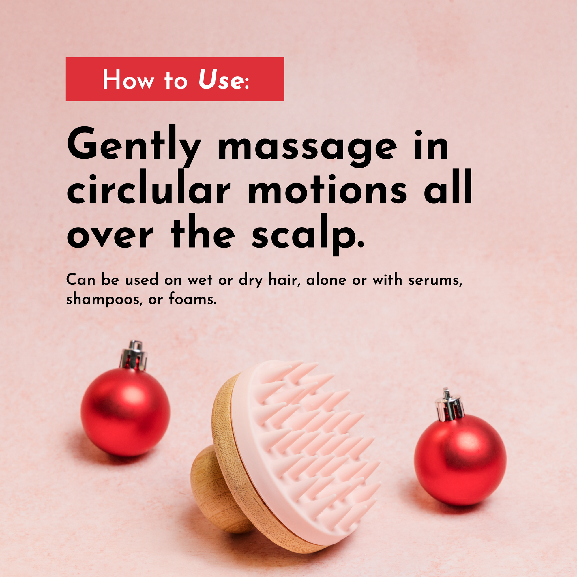 Scalp scrubber with a pink rubber head and wooden handle, placed next to red holiday ornaments on a pink background.