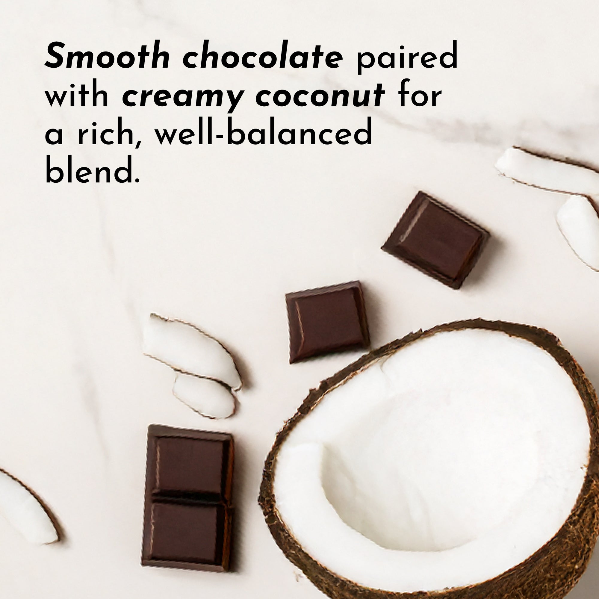 Coconut half with chocolate squares and coconut flakes on a light surface.