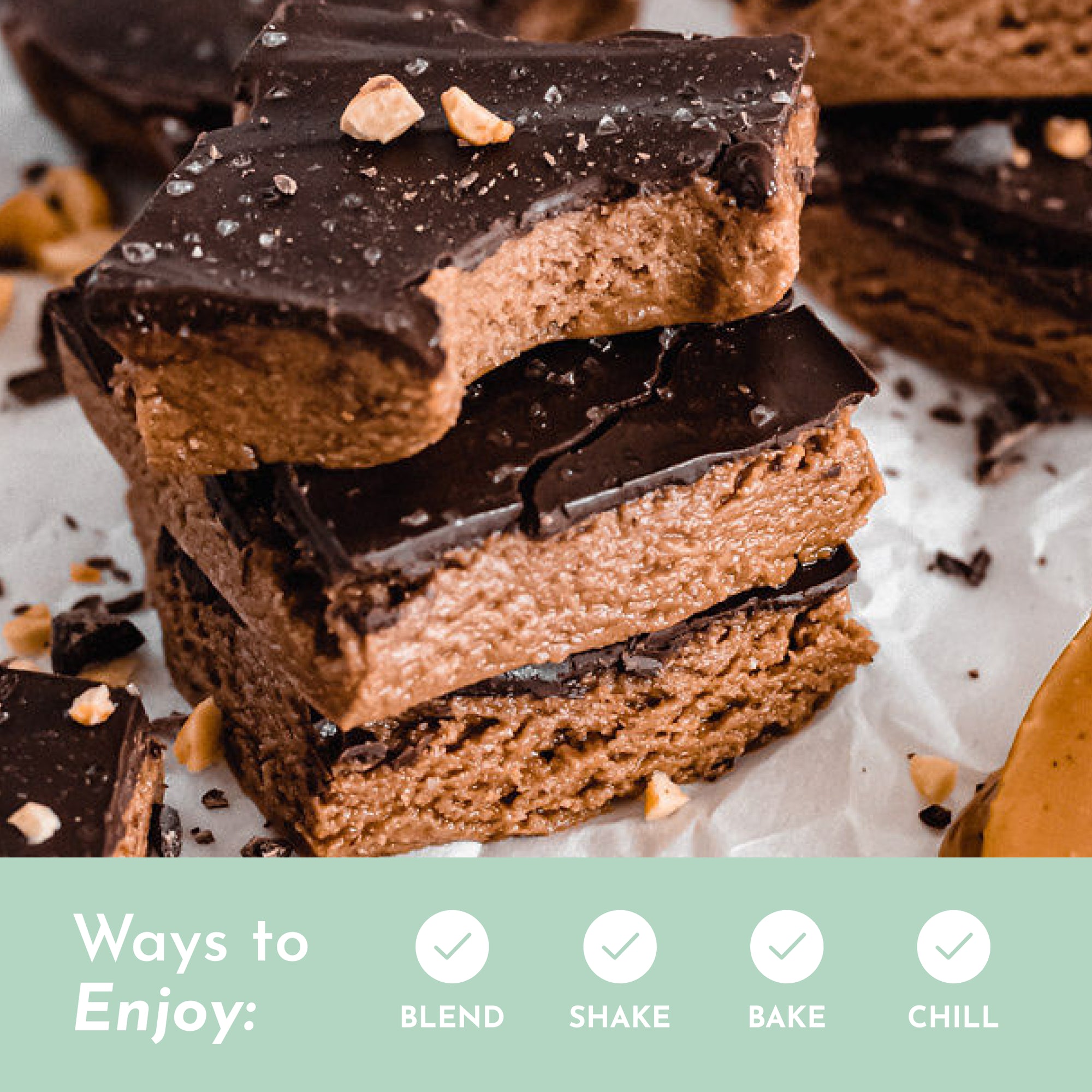 Stack of chocolate-covered protein bars with a bite taken out, sprinkled with nuts and sea salt.