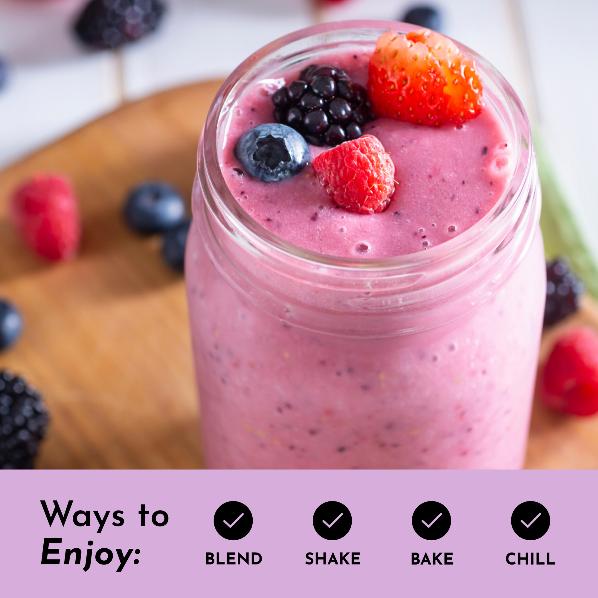 Smoothie in a glass jar topped with berries, placed on a wooden surface with scattered berries around.