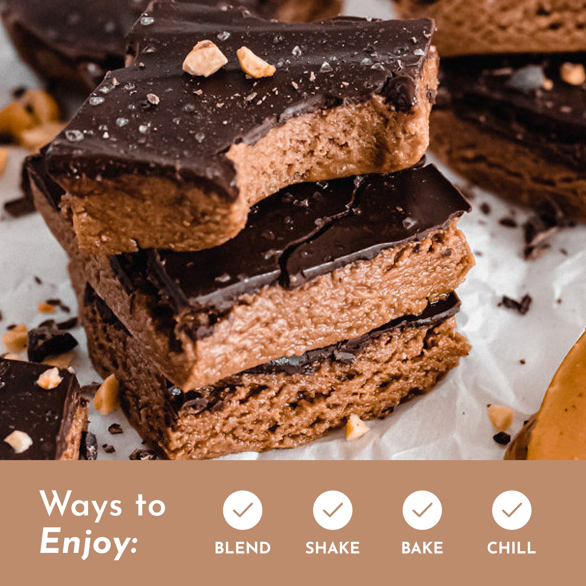 Stack of chocolate-covered protein bars with a creamy center and chopped peanuts on top, placed on parchment paper.