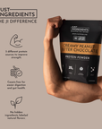 Black protein powder bag labeled "Creamy Peanut Butter Chocolate" held by a muscular arm, featuring nutritional details.