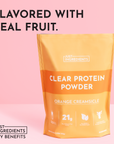 Orange Creamsicle clear protein powder bag with nutritional information on a pink background.