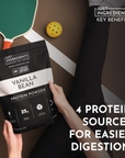 Black protein powder bag labeled "Vanilla Bean Protein Powder" held by a person, with a paddle and ball in the background.