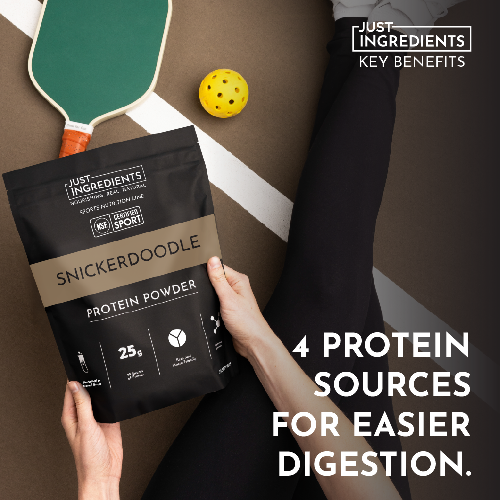 Black protein powder bag labeled "Snickerdoodle" held by a person, with a paddle and ball in the background.