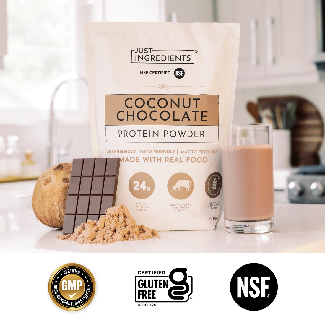 Coconut Chocolate protein powder bag beside a smoothie glass and a halved coconut on countertop.