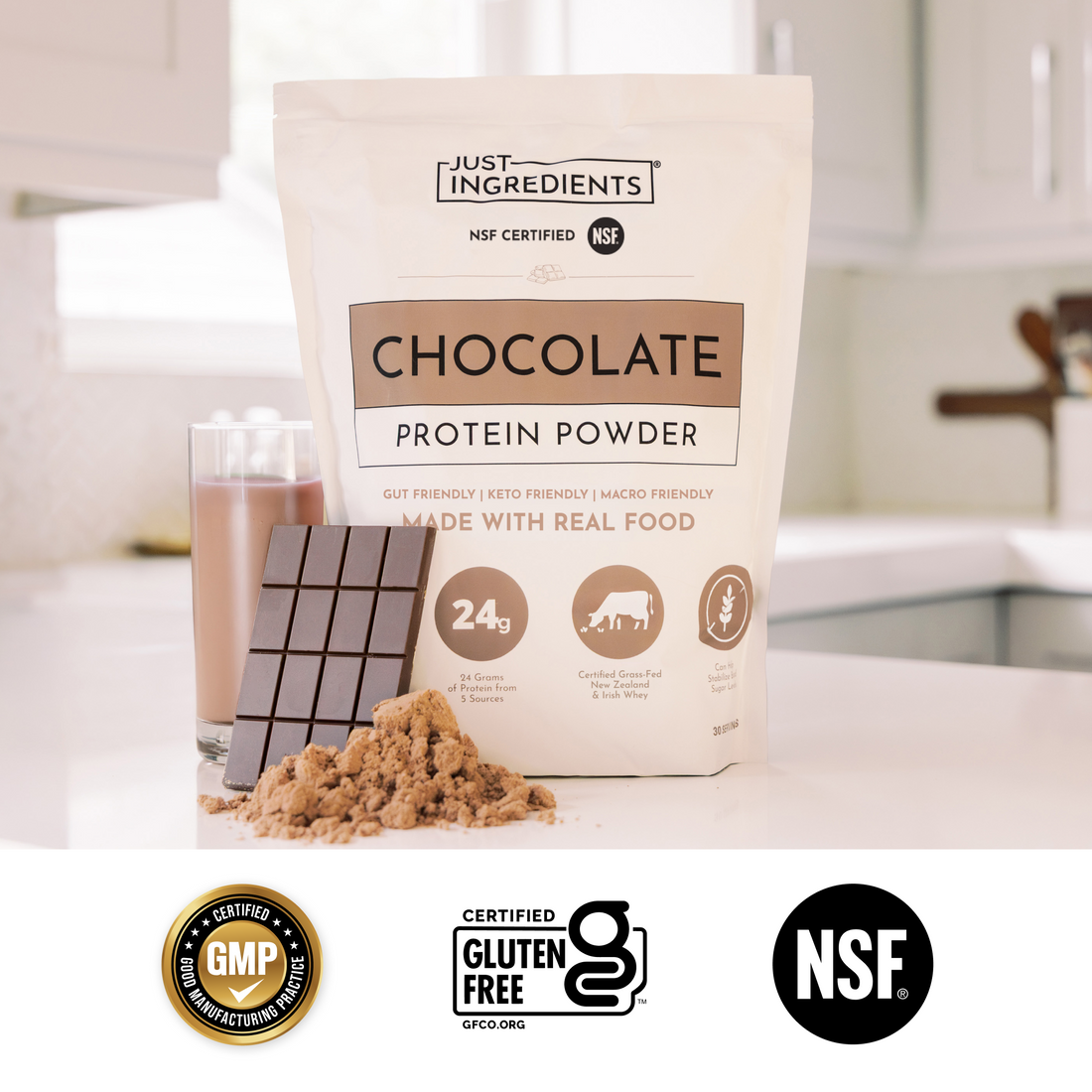 Chocolate protein bag next to a glass of shaken chocolate protein drink and a pink mixer.